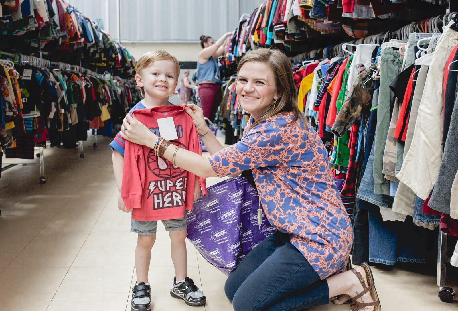 Mom holding a shirt up to little boy.